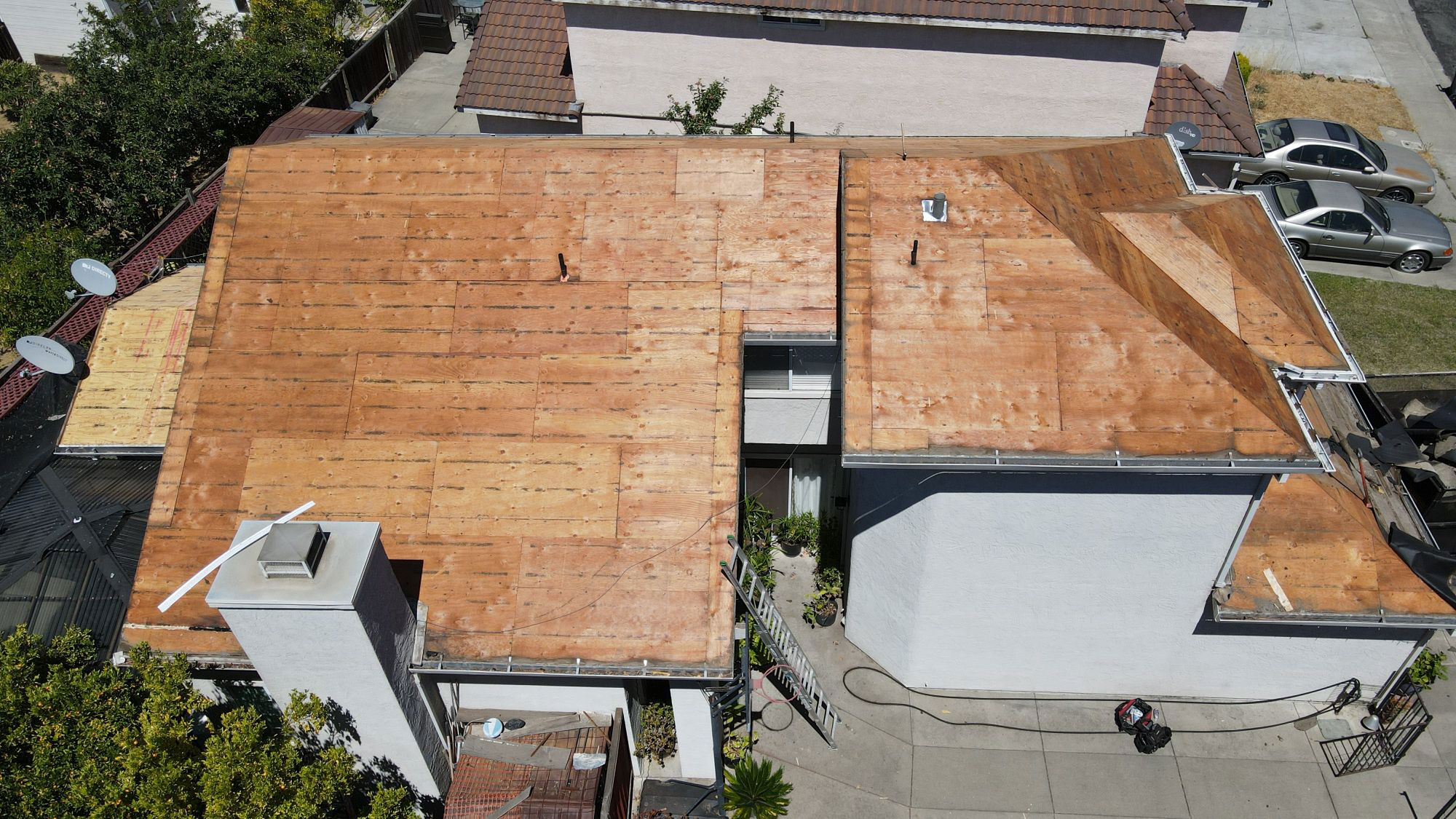 The image shows a house with a partially completed roof covered in brown shingles, indicating ongoing construction work.