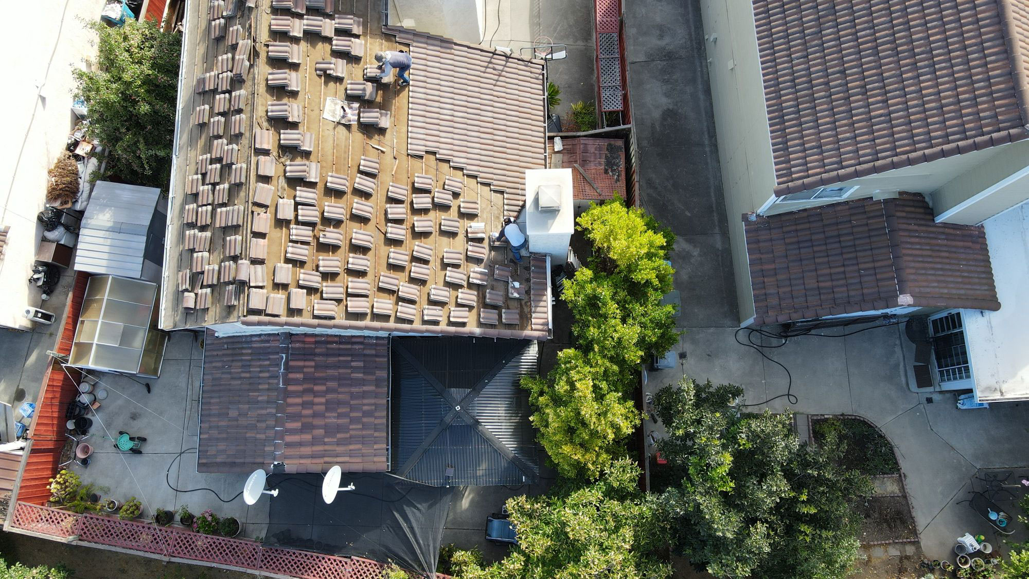 The image shows a residential area with a house under construction featuring a flat roof with solar panels installed.