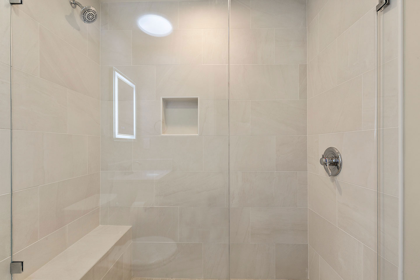 A modern bathroom with a clean white shower stall, beige tiles, and a minimalist design.