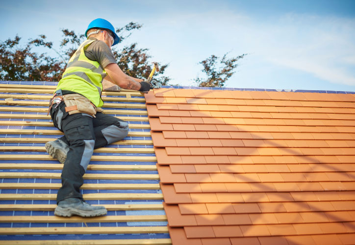 A construction worker on a roof, working on a sunroof installation.