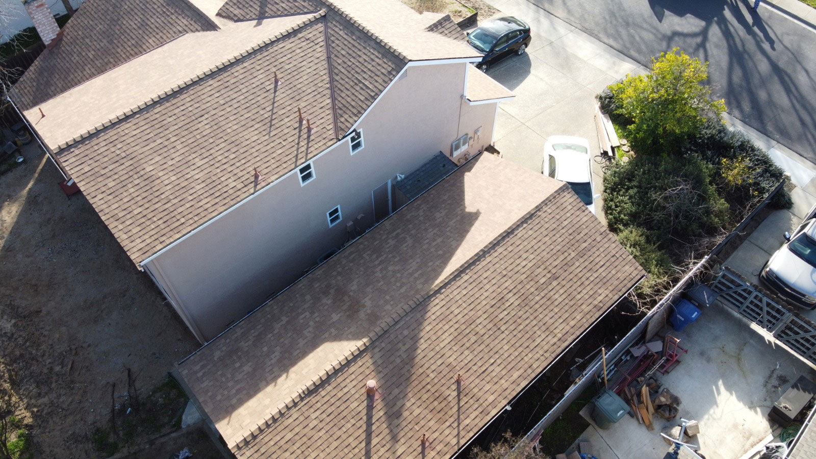 A photograph showing a two-story residential house undergoing roof replacement with visible shingles and construction materials.