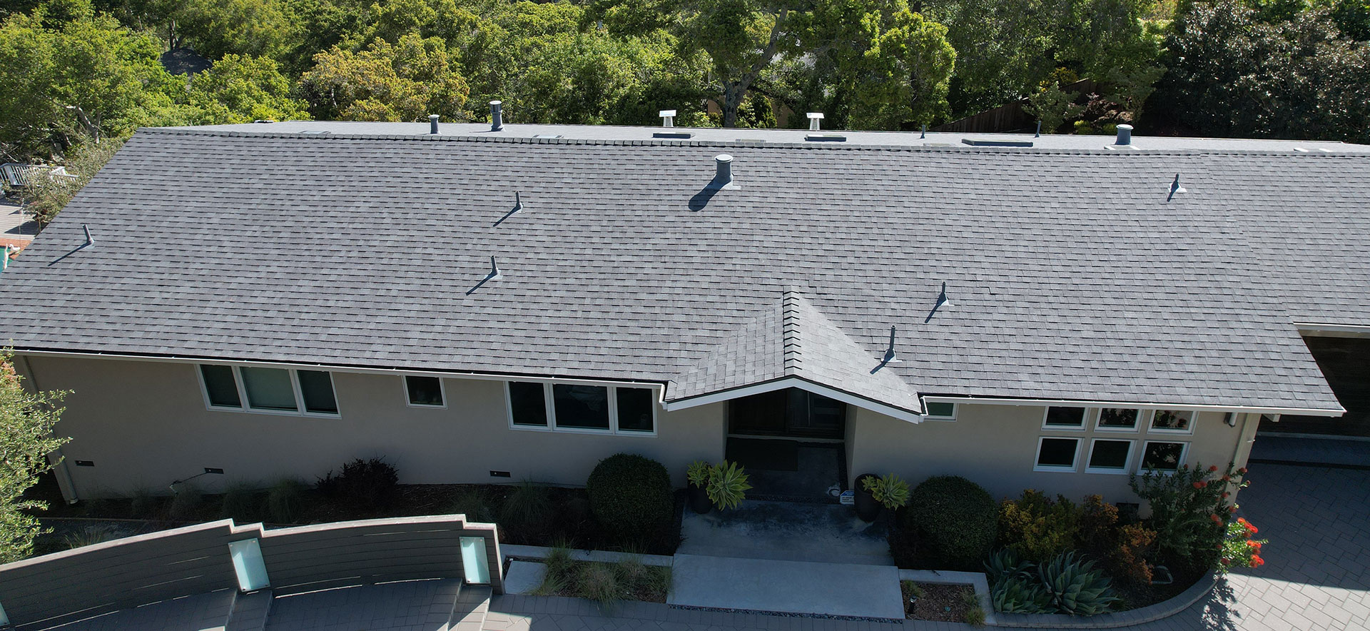 The image shows a two-story residential house with a sloped roof, exterior walls painted in a light color, and a garage visible at the front.
